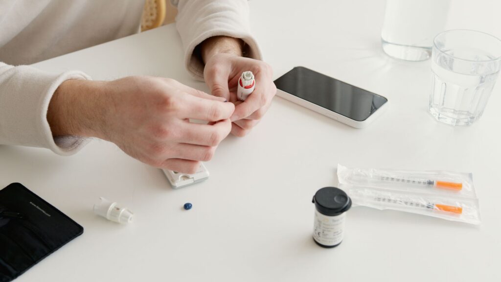 Person preparing an insulin injection with home glucose testing supplies